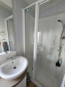 博斯Caravan 4 - Cambrian Coast Caravan Park的带淋浴和盥洗盆的白色浴室