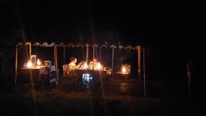 Kwa MhindaMakubi Safari Camp by Isyankisu的一群人坐在一张桌子上,在黑暗中