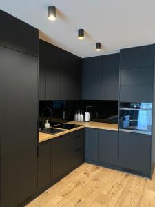 凯尔采Prestige Apartment Grabina的厨房配有黑色橱柜和水槽