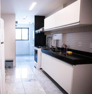 累西腓Nobile Residences Maria Frazão的厨房配有白色橱柜和黑色台面