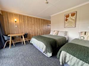 蒂阿瑙蒂阿瑙湖畔背包客旅馆的酒店客房设有两张床和一张桌子。