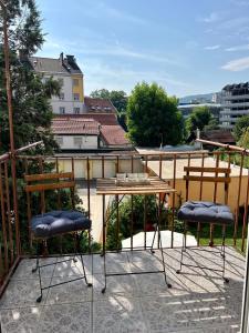 格拉茨Wohnung in Graz的阳台配有2把椅子和1张桌子