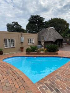 杰米斯顿Sapphire Guest House的一座大型蓝色游泳池,拥有茅草建筑