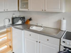 霍宁Tracara Cottage的厨房柜台设有水槽和微波炉