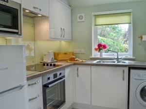 特伦Tigh Beag的厨房配有白色橱柜、水槽和窗户。