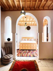 索维拉Riad Al Manara的一间卧室配有一张床、一把椅子和地毯