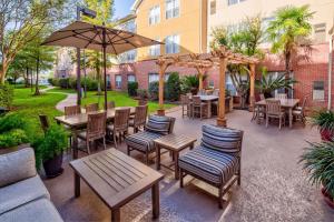 巴吞鲁日Homewood Suites by Hilton Baton Rouge的一个带桌椅和遮阳伞的庭院