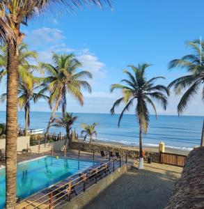 圣贝尔纳多德尔比恩托Apartamento 201 Palmar de los vientos的棕榈树和海洋海滩上的游泳池