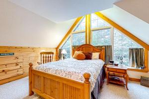 CarrabassettSugarloaf Chalet的一间卧室设有一张木床和一个大窗户。