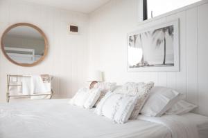 Te AraiAotearoa Surf Eco Pods的白色的床、白色枕头和镜子