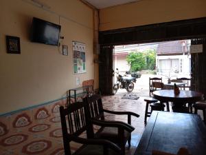 他曲Bami thakhek hostel的餐厅设有桌椅和墙上的电视