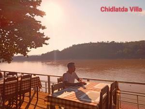 琅勃拉邦Mekong Chidlatda Villa的坐在桌子旁的水面上的人