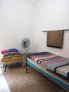 瓜拉弄宾Roomstay homestay Ahmad Rompin的一间卧室配有两张床和一张带风扇的桌子。