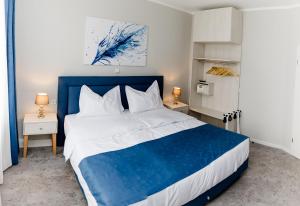 塔勒Aneton Garni Hotel的卧室配有蓝色和白色的床和两张桌子