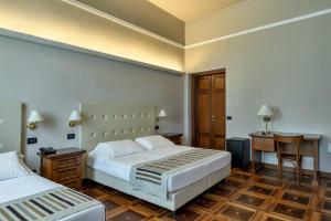 曼托瓦Hotel Antica Dimora的酒店客房配有两张床和一张书桌