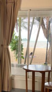 Ban Pak NamLaemsing Natural Beach Resort的一张桌子和一个享有海滩美景的窗户