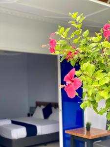 迪古拉Tides Dhigurah的一间卧室配有床和种有粉红色花卉的植物