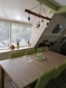 杜柏The Green Apple Durbuy的一间带木桌和绿色椅子的用餐室