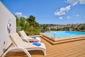 梅利哈Villa Goa - By Luxury Villas Malta的一个带两把椅子的甲板和一个游泳池