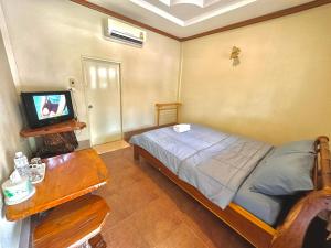 Ban Nam Mongโรงแรมแสงทองรีสอร์ท的一间卧室配有一张床、一台电视和一张桌子