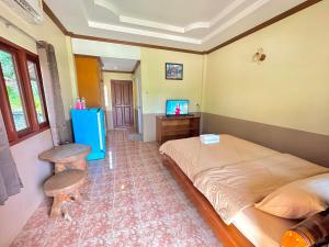 Ban Nam Mongโรงแรมแสงทองรีสอร์ท的一间卧室配有一张床、一张桌子和一台电视