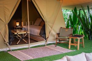 清迈CAMP CAYLA - EDEN的帐篷配有1张床、1张桌子和1把椅子