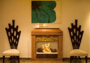 钱德加尔Blueberry Hotel zirakpur-A Family hotel with spacious and hygenic rooms的壁炉,壁炉内有火,配有两把椅子