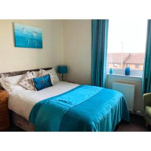 福尔柯克Scardroy Falkirk - 3 Bedroom Apartment的一间卧室配有一张带蓝色床单的床和一扇窗户。