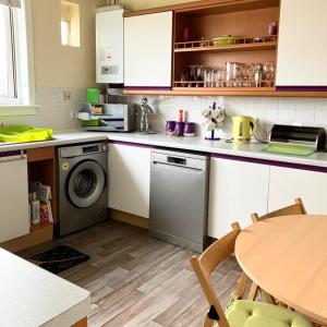 福尔柯克Scardroy Falkirk - 3 Bedroom Apartment的厨房配有洗衣机和桌子