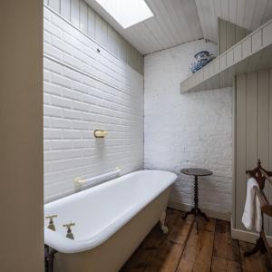 都柏林Merrion Mews的浴室设有白色砖墙,配有浴缸。