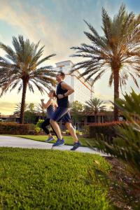 奥兰多DoubleTree by Hilton Hotel Orlando at SeaWorld的两个人沿着棕榈树的路边跑