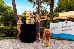 奥兰多DoubleTree by Hilton Hotel Orlando at SeaWorld的两个女人和一只狗站在桌子旁边