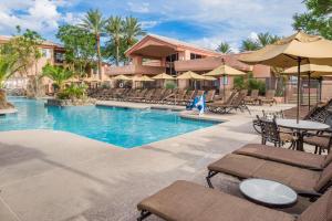 斯科茨Hilton Vacation Club Scottsdale Villa Mirage的一个带桌椅和遮阳伞的度假游泳池
