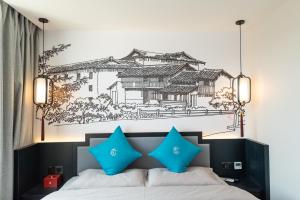 昆明龚禧里·璞见酒店(昆明翠湖云南大学店）的一张带蓝色枕头的床和墙上的画