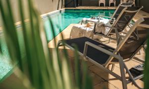 布里斯班伊尔盟多精品酒店的游泳池畔的两把椅子和一张桌子