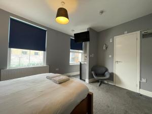 伦敦Small Double Studio close to King's Cross & Camden的一间卧室配有一张床、一把椅子和窗户。