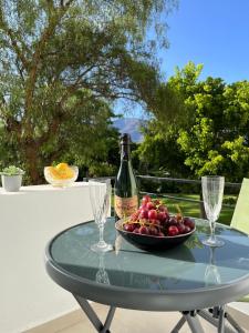 EsteponaGolden Bay Apartment的玻璃桌,带一瓶葡萄酒和一碗水果