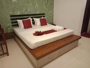 阿努拉德普勒Monaara Leisure - Anuradhapura的一间卧室配有一张带红色和白色枕头的大床