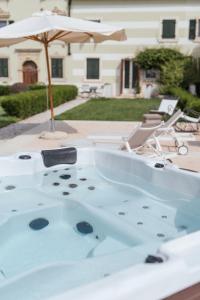 维罗纳Madonna Villa Baietta的庭院内的按摩浴缸和遮阳伞