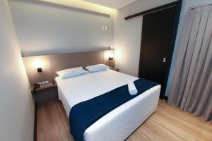 坎博里乌Arco do Sol Park Hotel的一间卧室配有一张大白色床和蓝色毯子