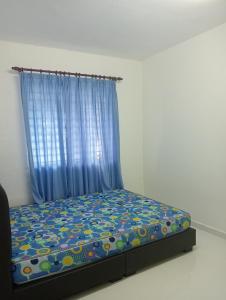 万挠SERI BAKAWALI HOMESTAY的一间卧室配有一张蓝色窗帘的床