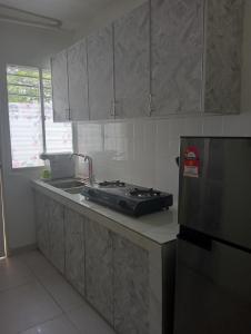 万挠SERI BAKAWALI HOMESTAY的厨房配有水槽、炉灶和冰箱