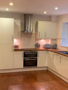 沃金厄姆Wokingham - Large 2 bedroom Apartment的厨房配有白色橱柜和炉灶烤箱。