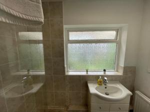 沃金厄姆Wokingham - Large 2 bedroom Apartment的一间带水槽和淋浴的浴室以及窗户。