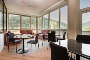 韦扎多廖Hotel Vezza Alpine Lodge & Spa的餐厅设有桌椅和窗户。