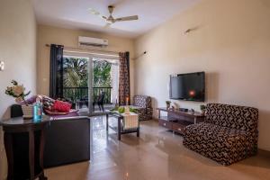 巴加Goa Chillout Apartment - 1BHK, Baga的客厅配有电视、椅子和桌子