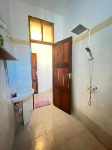 帕杰Mauwa House的一间带水槽和淋浴的浴室以及一扇门