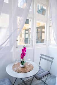 弗洛里亚纳Valletta Waterfront 2 Beds Flat的一张桌子,上面有两杯眼镜,花瓶上放着鲜花