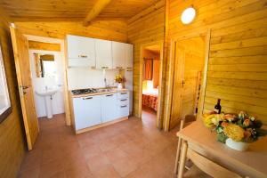 托雷德尔格拉戈普奇Camping dei Tigli的小屋内的厨房配有白色橱柜和桌子