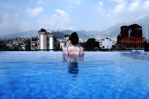加德满都Divine Kathmandu Hotel的游泳池里拍城市照片的女人